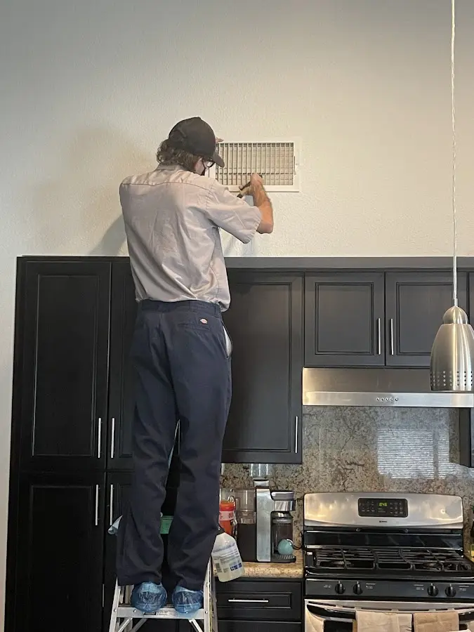 Technician inspecting an air vent during HVAC service in Selma